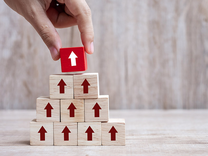 envisionglobal-blog_are_you_a_transformational_leader_businessman_hand_placing_or_pulling_red_arrow_wooden_block_on_table_background._business_0